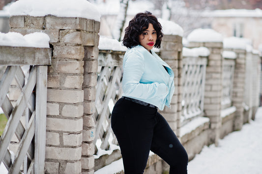 Woman in jeans and denim jacket posing in the snow.